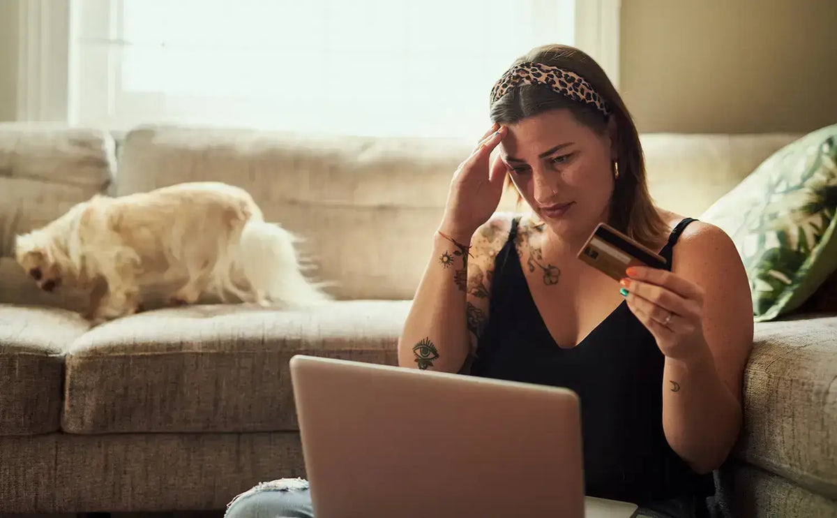 Femme regardant un ordinateur portable en tenant une carte de paiement.
