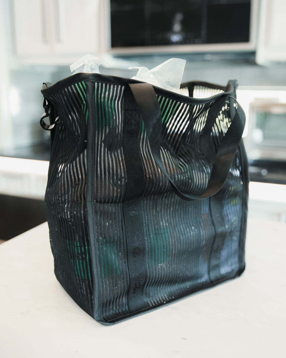 Sac Non Insulated Organizer Bag en maille, rempli et posé sur un plan de travail de cuisine.