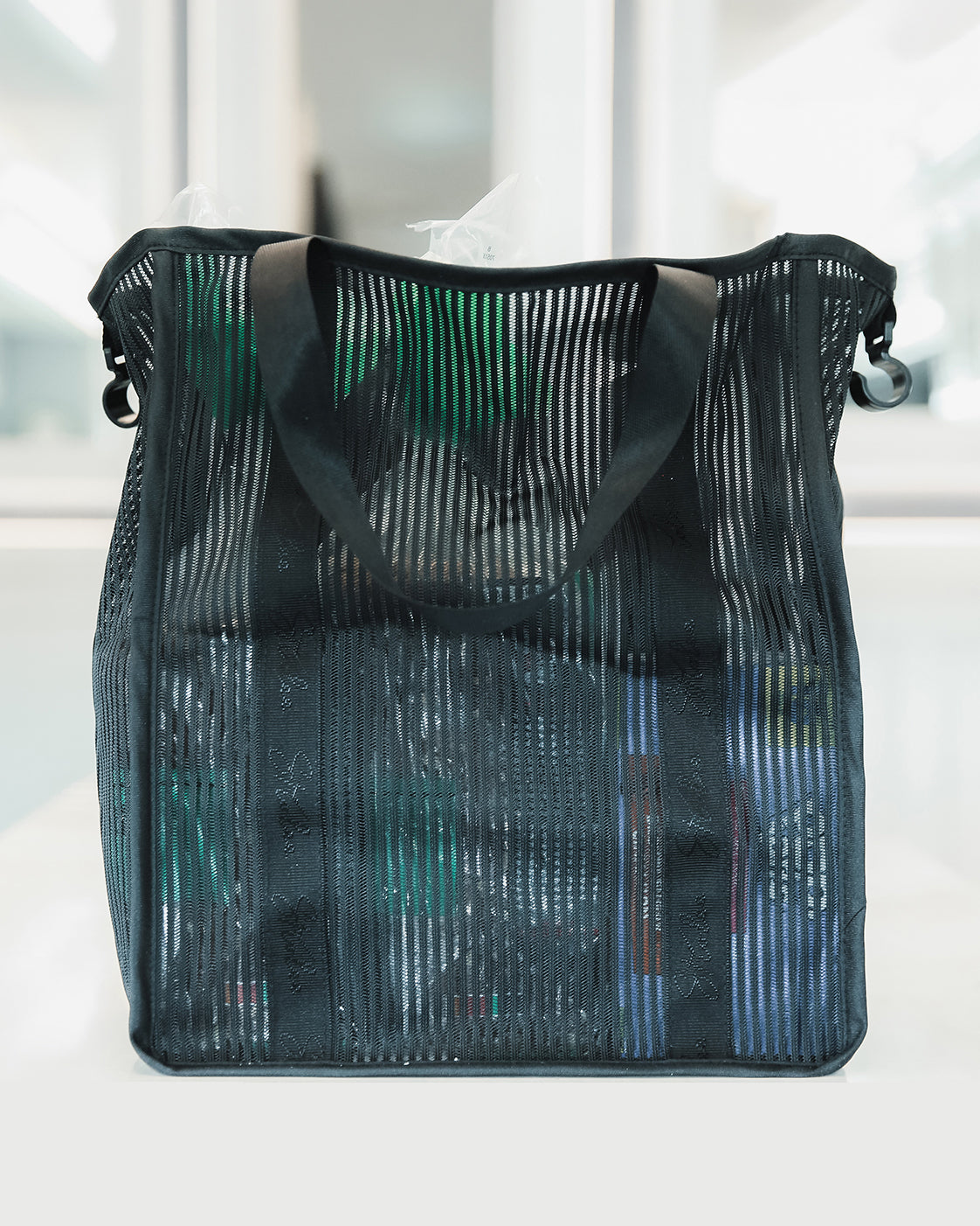 Vue de face d’un sac de rangement en maille, dont le contenu est visible à travers le tissu.