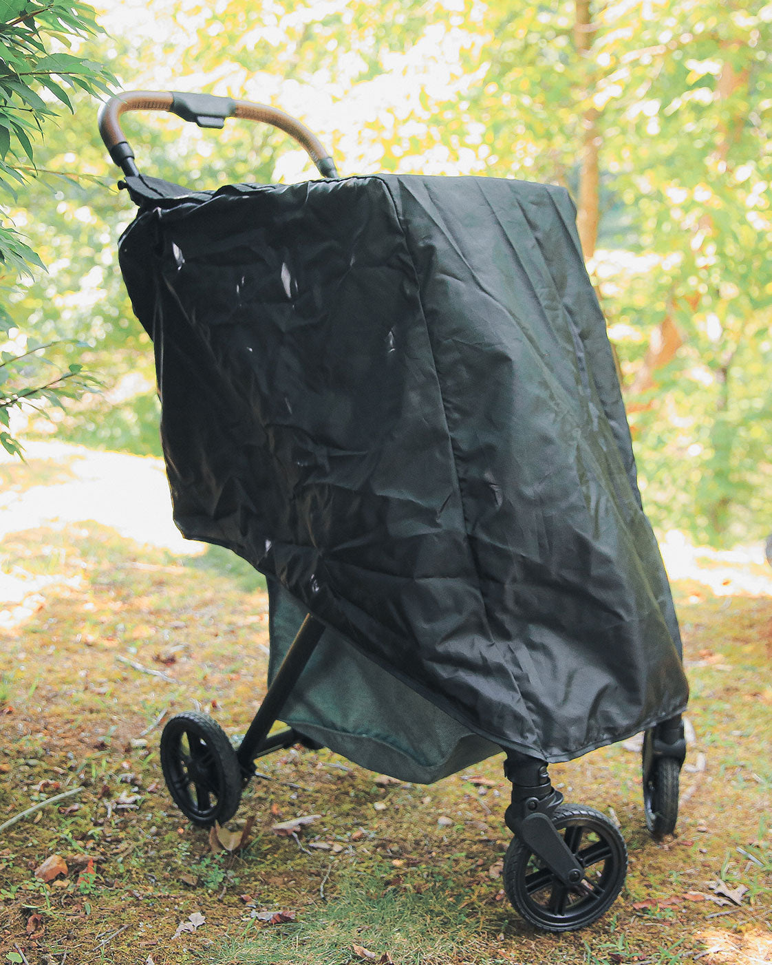 Rain Cover, coloris Black, installé sur un chariot Strolee à l’extérieur.