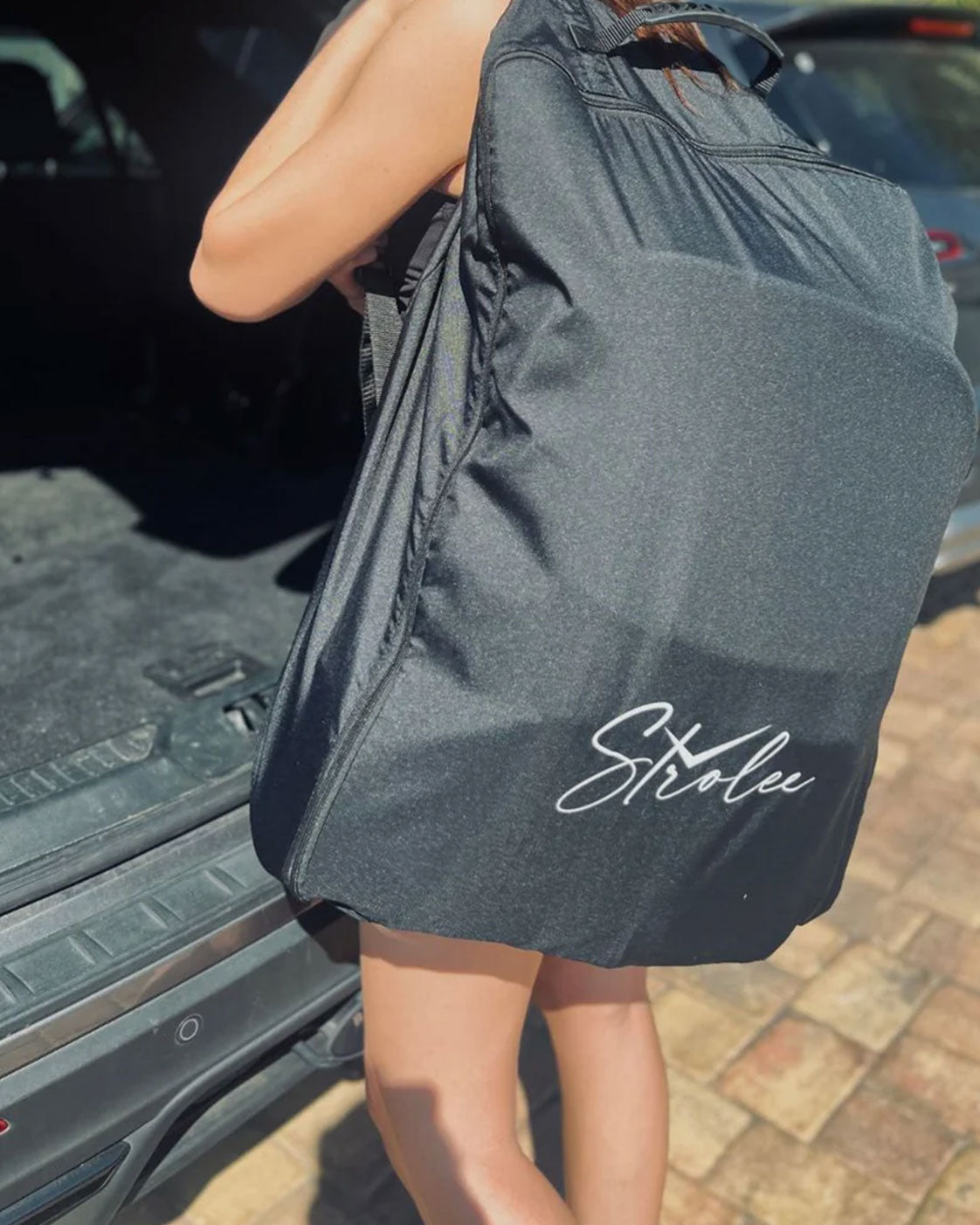 Woman carrying the black Strolee Travel Backpack over her shoulder.