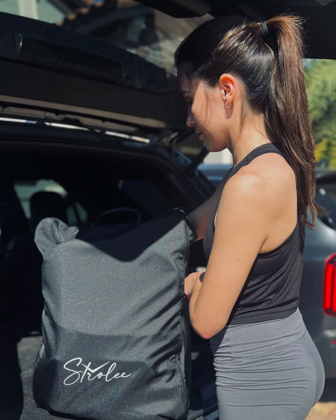 Woman holding the packed Travel Backpack beside an open car boot.