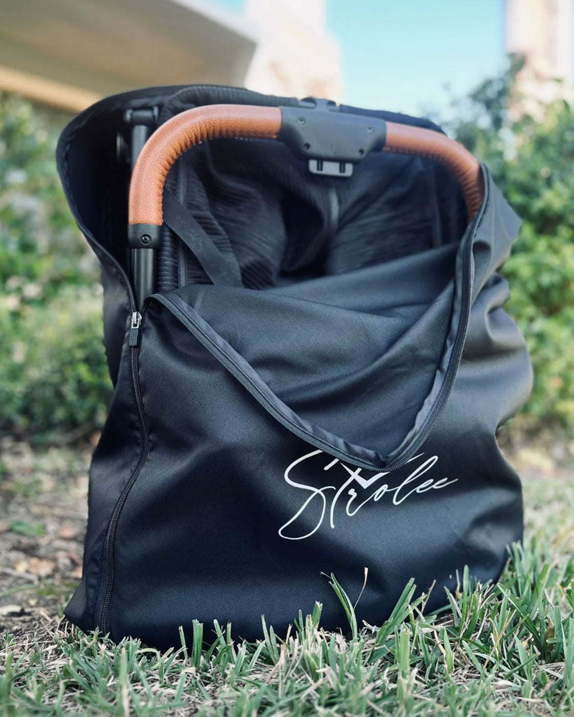 Travel Backpack open around a folded Strolee cart, with its handle visible.
