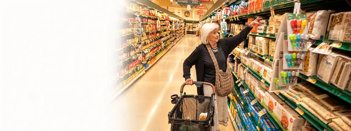 Frau beim Einkauf im Supermarkt mit einem Wagen voller Lebensmittel.