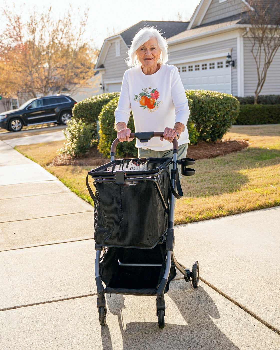 Frau geht mit einem Stability Shopper auf einem Gehweg in einem Wohngebiet.